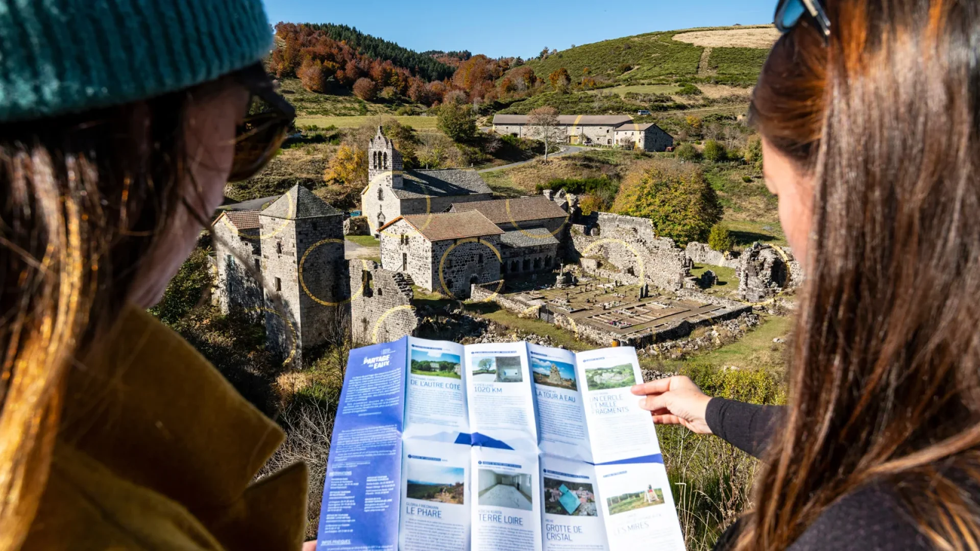 Two women looking at a map in front of Felice Varini's golden circles, a Watershed work, at Mazan Abbey, in autumn
