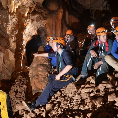 Group of teenagers practicing caving with a guide