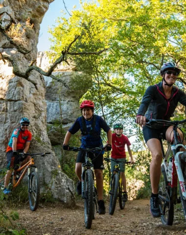 Family with teenagers mountain biking in the Païolive woods in summer