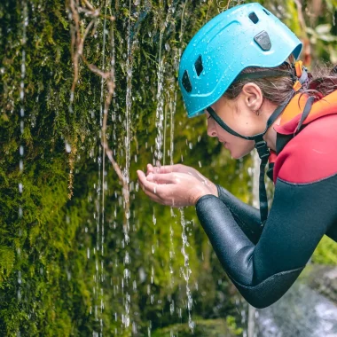 Teenage girl touching flowing water during a canyoning trip