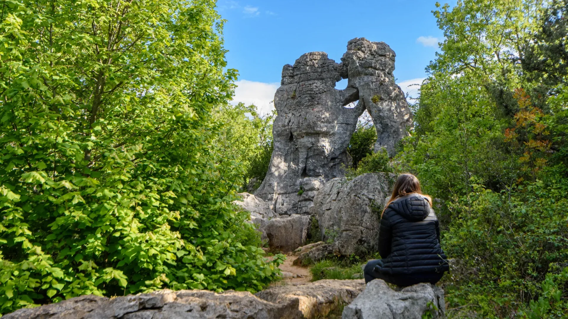 Woman observing the “bear and the lion” of the Bois de Païolive in spring