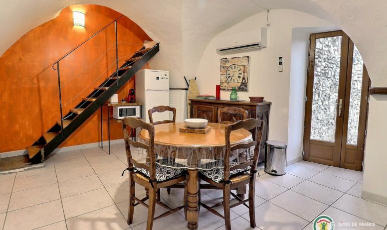 Gîtes de France - Pièce de vie avec cuisine équipée, table ronde pour les repas et accès terrasse