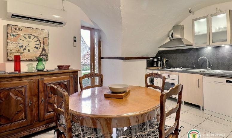 Gîtes de France - Pièce de vie avec cuisine équipée, table ronde pour les repas et accès terrasse