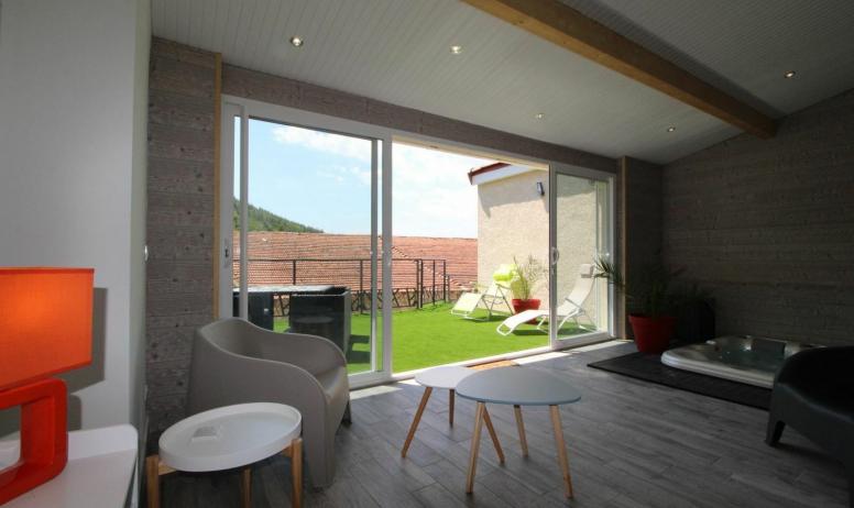 Gîtes de France - Espace salon dans la véranda avec jacuzzi encastré et privatif à l'appartement, et vue sur la terrasse